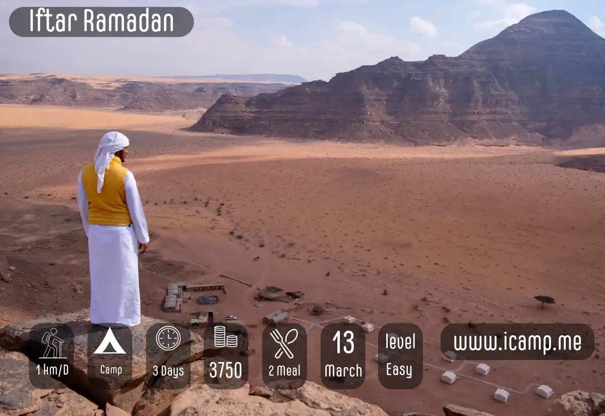 A bedouin man standing on top of a mountain overlooking a mountain valley