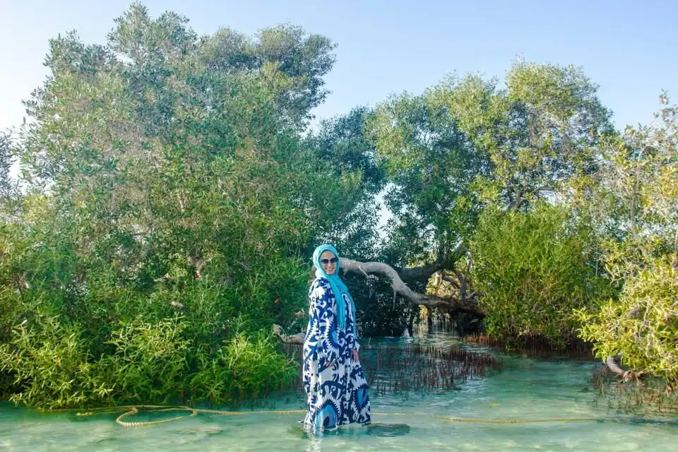 A woman standing in a shallow sea water behind her a mangrove tree in Marsa Alam